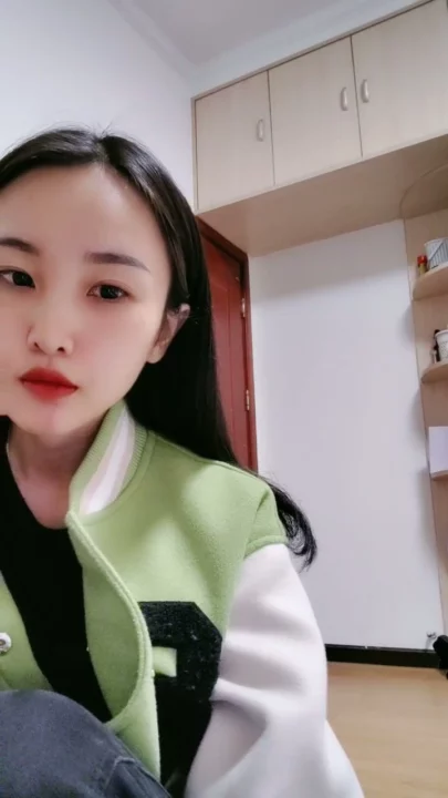 Screenshot 2 aus Petite Asiatin solo am Teasen — Varsity-Jacke und verführerische Posen im Studentenzimmer